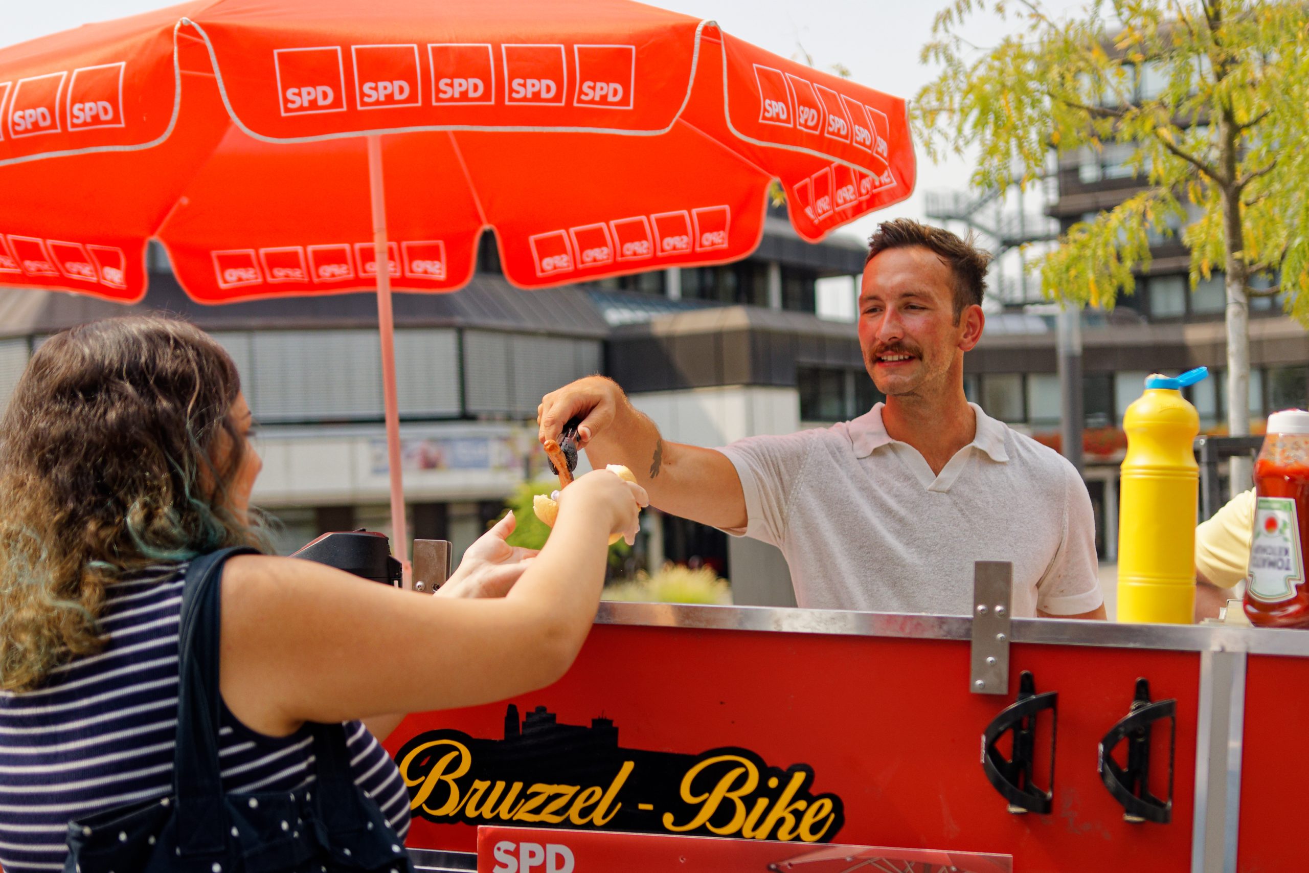 Simon Skibitzki (Landtagskandidat der SPD für den Wahlkreis Rhein-Sieg V) gibt eine vegane Bratwurst aus